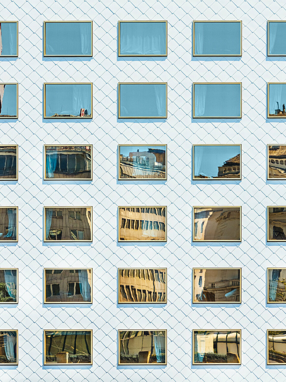 Fasáda hotelu THE ROCK Radisson RED Vienna, navržená ateliérem INNOCAD, z normální perspektiv. Můžete vidět řadu čistě bílých nástěnných kosočtvercových šablon a zrcadlově zasklených oken, které obklopují okolí.